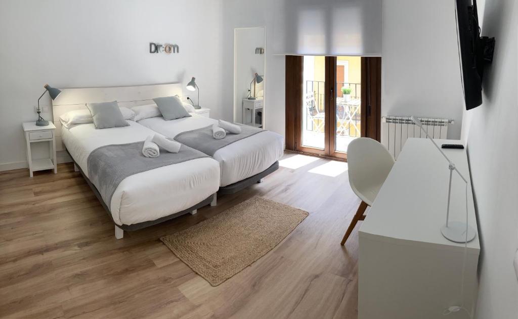 um quarto branco com 2 camas e uma mesa em TeruelHOME II em Teruel