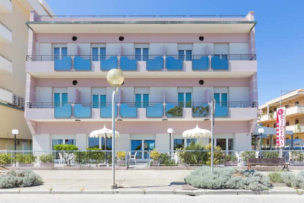 een groot roze gebouw met blauwe balkons bij Hotel Ridens in Rimini