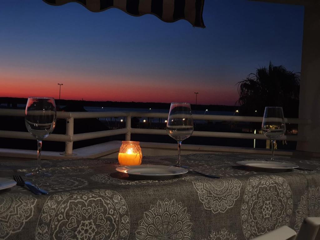 una mesa con tres copas de vino y una vela en ella en Avenida de las Piletas, en Sanlúcar de Barrameda