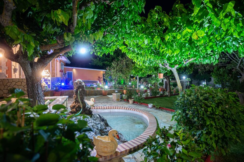 una piscina con patos en un jardín por la noche en Rock Garden Villa en Marantochori