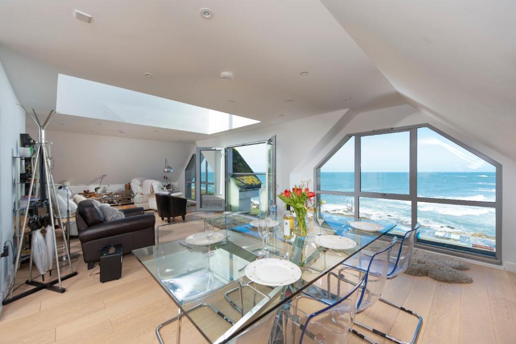 un soggiorno con tavolo in vetro e vista sull'oceano di Fistral beach Penthouse, Newquay a Crantock