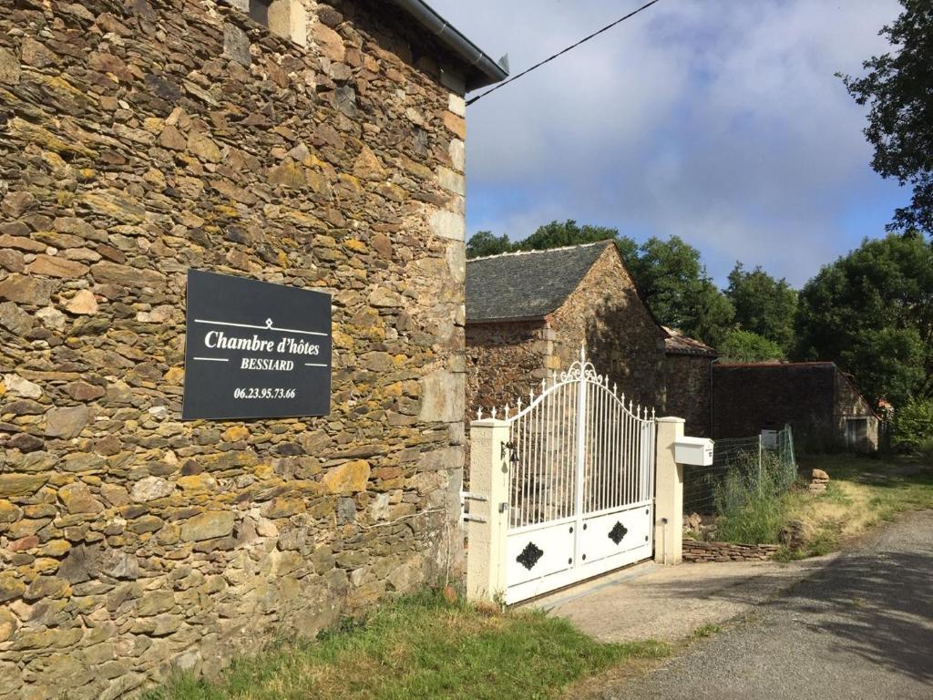 een bord aan de zijkant van een stenen gebouw met een poort bij Chambre d'hotes Bessiard in Laparrouquial