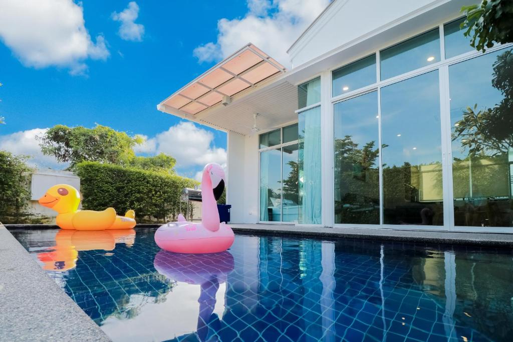 a swimming pool with two inflatable ducks in a house at Chaum Haus Pool Villas in Cha Am