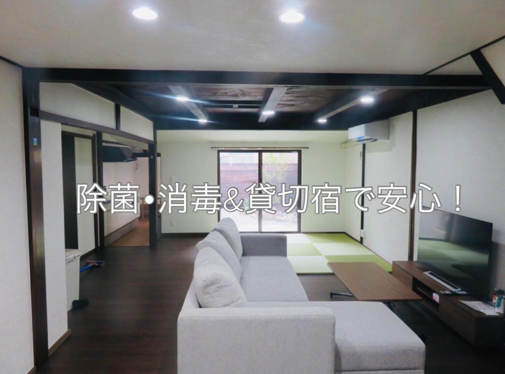 uma sala de estar com um sofá branco e uma televisão em Utatei Nada em Takayama