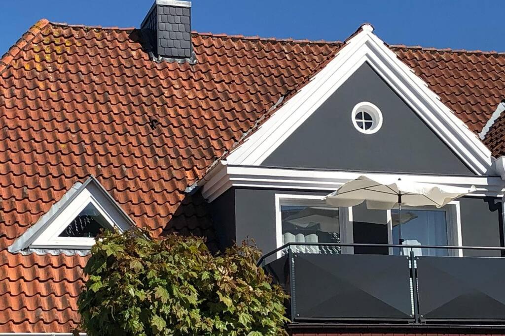 a house with a roof with an umbrella on a balcony at Schöner (Ferien-) Wohnen in Bad Laer in Bad Laer