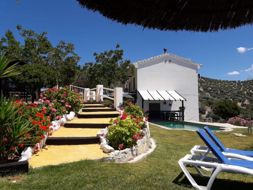 a resort with a pool and flowers and a building at La Choza De Mamuyo in Montefrío