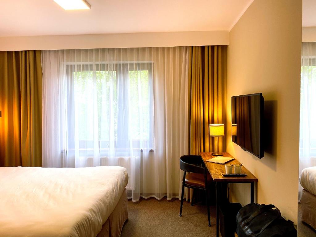 Pokój hotelowy z łóżkiem, biurkiem i oknem w obiekcie Amber Blue Wellness & SPA w Karwii