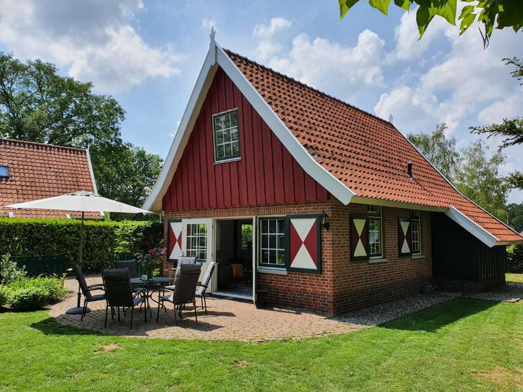a red barn with a table and chairs in the yard at Lekker Plekje Achterhoek in Lievelde