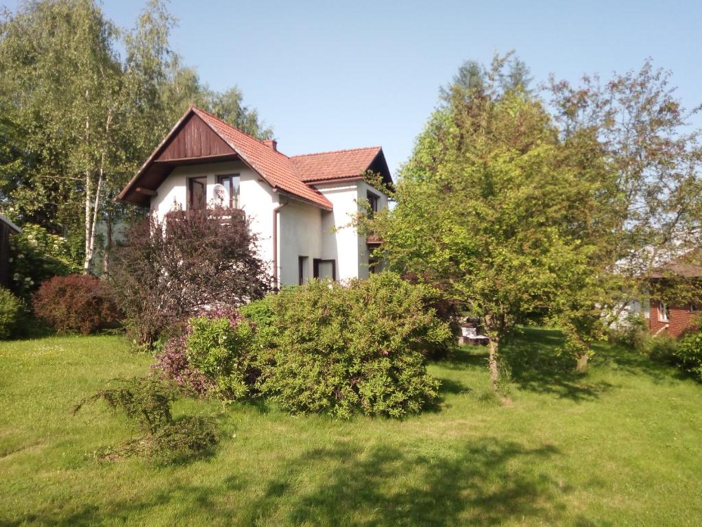una casa en un patio de césped con árboles y arbustos en Wolscy Blachnickiego 3, en Krościenko nad Dunajcem