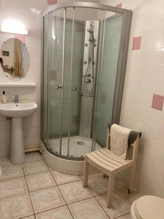 uma casa de banho com um chuveiro, um WC e uma cadeira. em Poppys Chambres d'Hotes em Céret