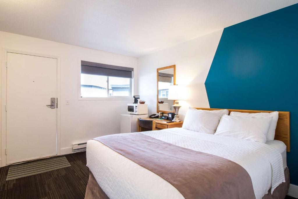 a bedroom with a large bed and a blue wall at Stoke Hotel SureStay Collection by Best Western in Revelstoke