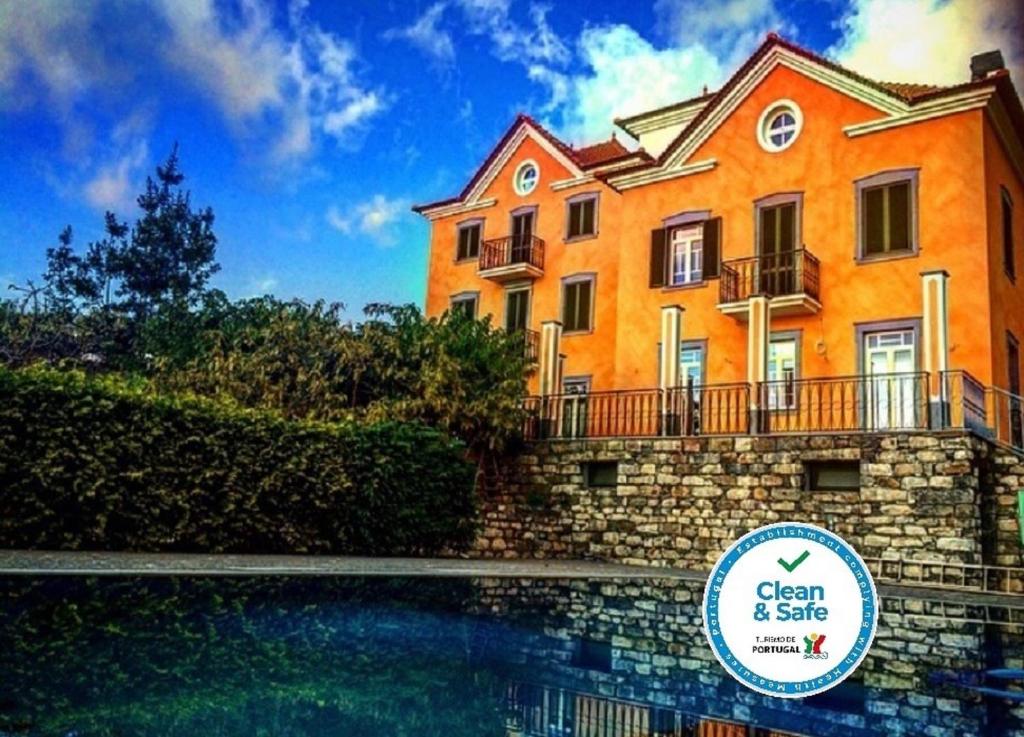 um grande edifício laranja com uma piscina em frente em Quinta Paços do Lago no Funchal