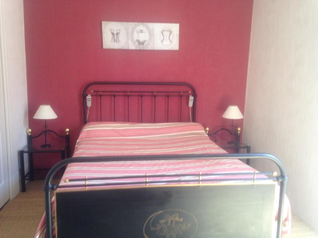 a bed in a room with a red wall at Les Fleurs in Monpazier