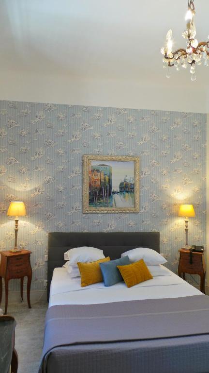 a bedroom with a large bed with blue and yellow pillows at Hotel Relais Du Postillon in Antibes