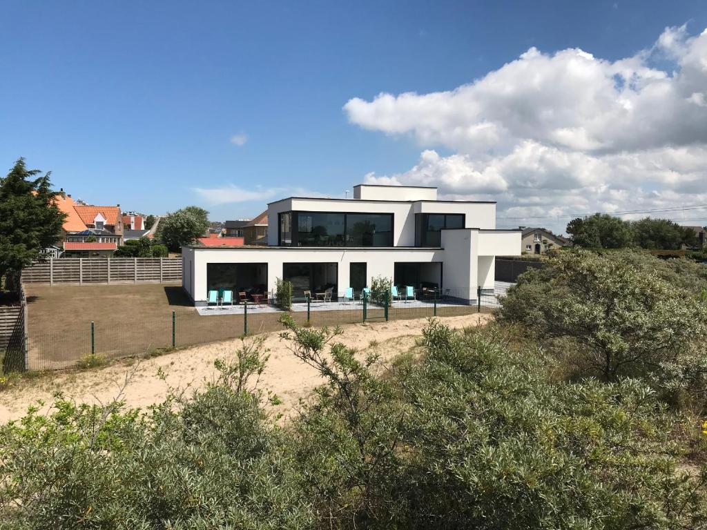 a large white house on a hill with trees at Whaaw Westende-bad in Middelkerke