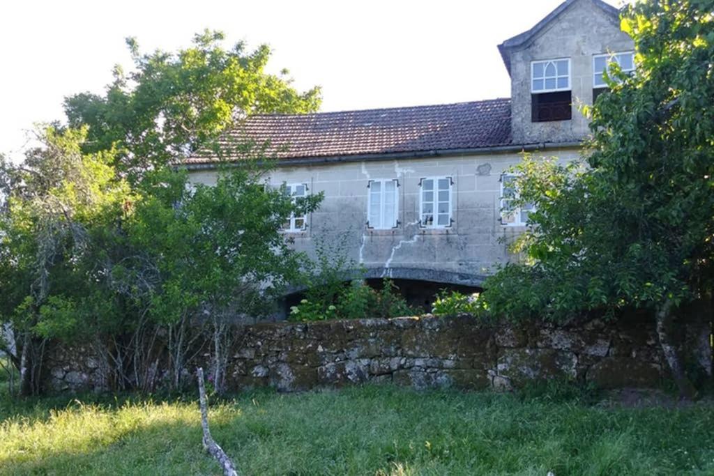 een oud stenen huis achter een stenen muur bij Casa "A Rúa" - Preciosa casa en la montaña con amplio jardín in Vilariño