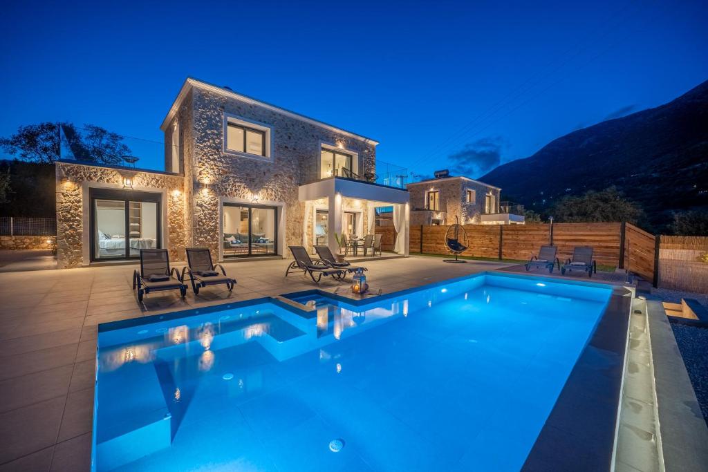 a villa with a swimming pool at night at Diosas Luxury Villas in Pilaroú