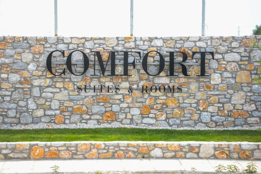 un cartello sul lato di un muro di pietra di Comfort Suites & Rooms a Larisa