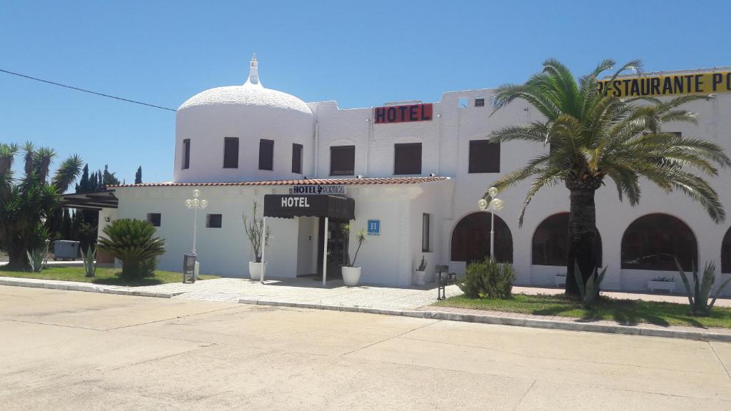 un edificio blanco con una palmera delante en Hotel Portugal, en Lepe