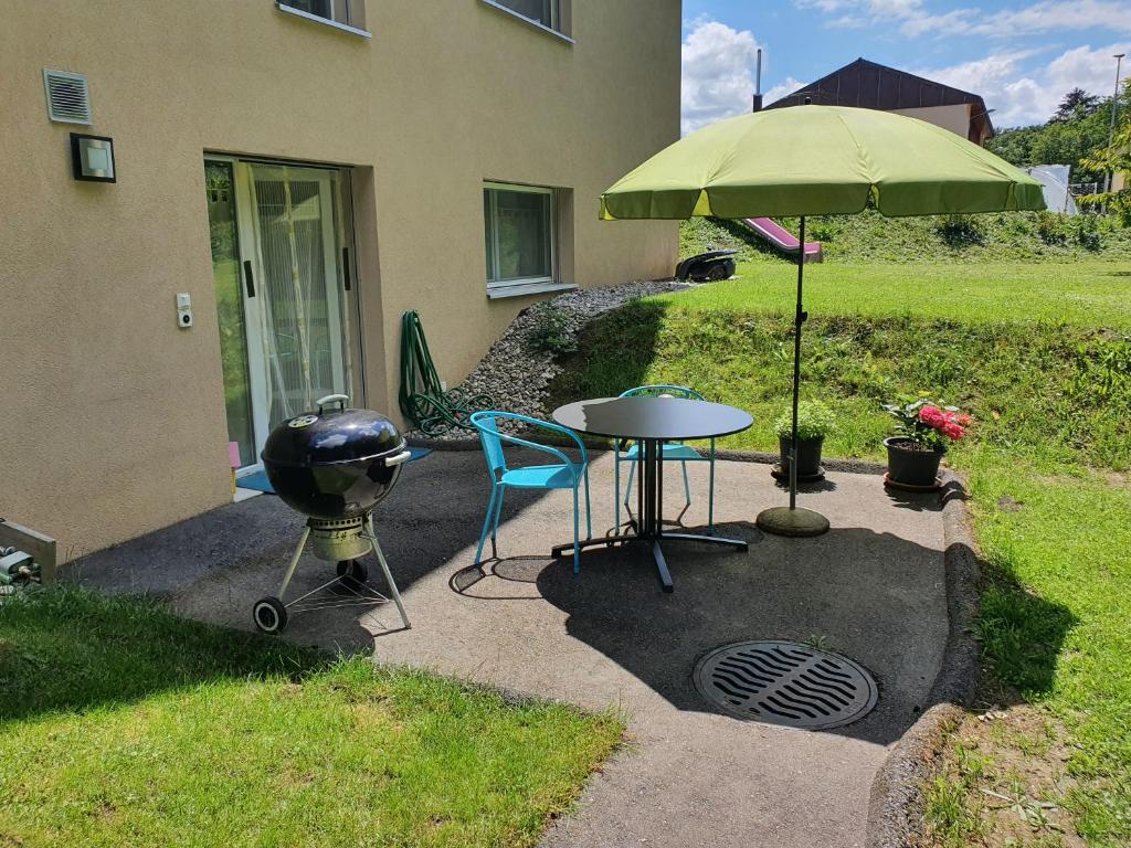 een grill en een tafel met een groene parasol bij Gîte La Broye in Surpierre