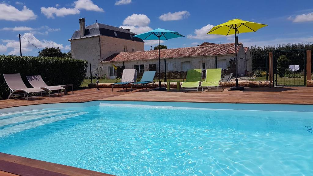 a swimming pool with chairs and umbrellas on a patio at le domaine de bellevue in Tanzac