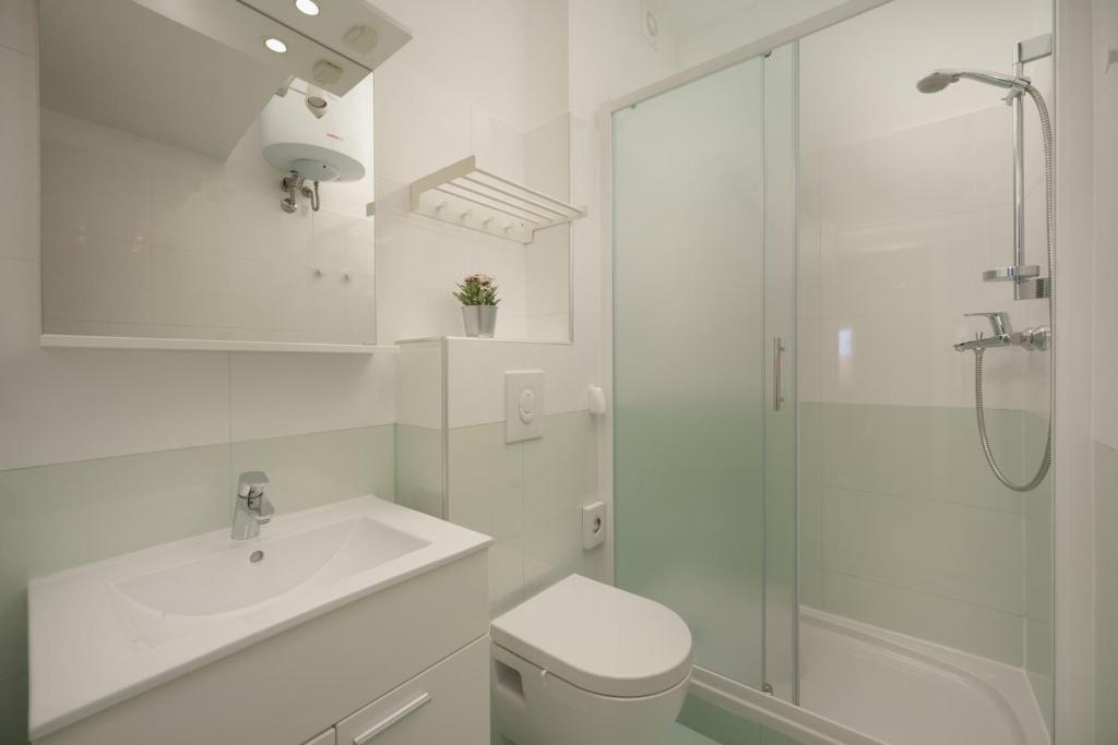 biała łazienka z umywalką i prysznicem w obiekcie Apartments Antons w Puli