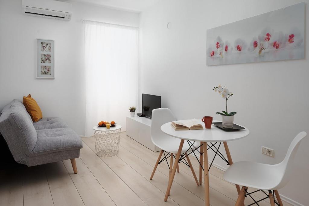 a white living room with a table and a chair at Apartments Antons 2 in Pula