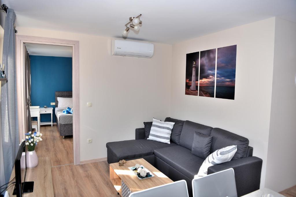 ein Wohnzimmer mit einem schwarzen Sofa und einem Tisch in der Unterkunft New Fortress Corfu Apartment in Korfu-Stadt