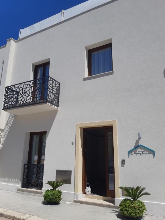 a white building with a door and a balcony at L'Angolo Dello Zio in San Vito lo Capo