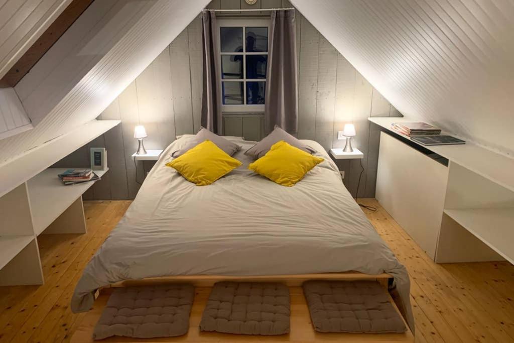 a large bed with two yellow pillows in a attic at Petit loft SAINT-MALO intra-muros in Saint Malo