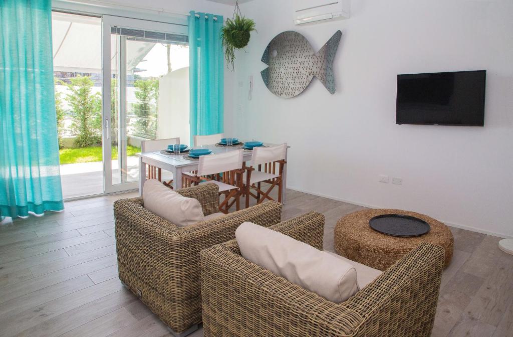 a living room with chairs and a table and a television at MARINA PONENTE in Lido di Jesolo
