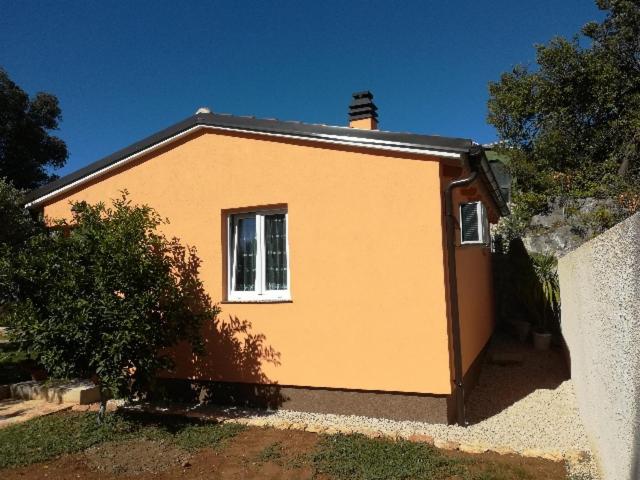 a small yellow house with a window on it at Apartman Sabljak-Nerezine in Mali Lošinj