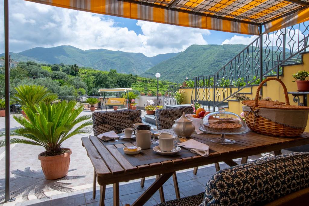 einen Holztisch auf einer Terrasse mit Bergen im Hintergrund in der Unterkunft B&B L'Abbraccio in Casola di Napoli