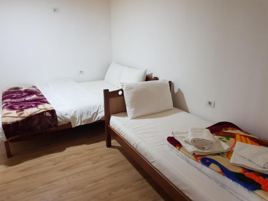 two beds in a room with white walls at Bujtina Sherifaj in Valbonë