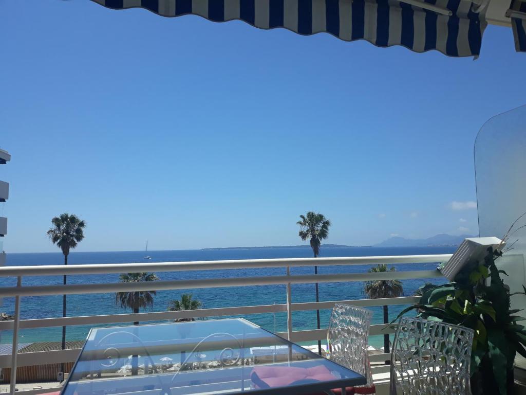 una mesa y sillas en un balcón con vistas al océano en Le Palais du Tropique appartement vue mer 5é étage avec ascenseur, en Juan-les-Pins