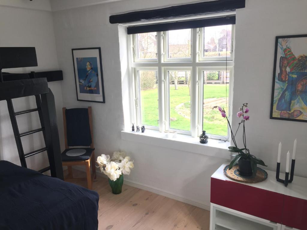 a bedroom with two windows and a table with flowers at Revninge Guesthouse in Revninge