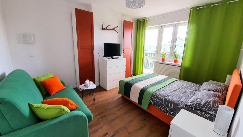 ein Schlafzimmer mit einem grünen Bett und einem Sofa in der Unterkunft Apartament Jeleń in Hajnówka