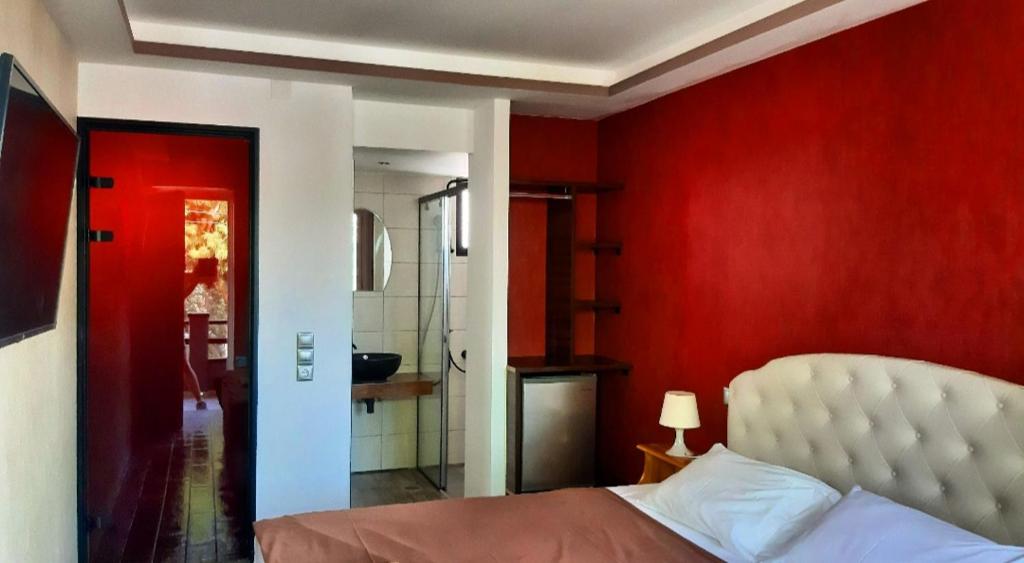 1 dormitorio con paredes rojas, 1 cama y baño en Villa Park Luxury Rooms, en Paralio Astros