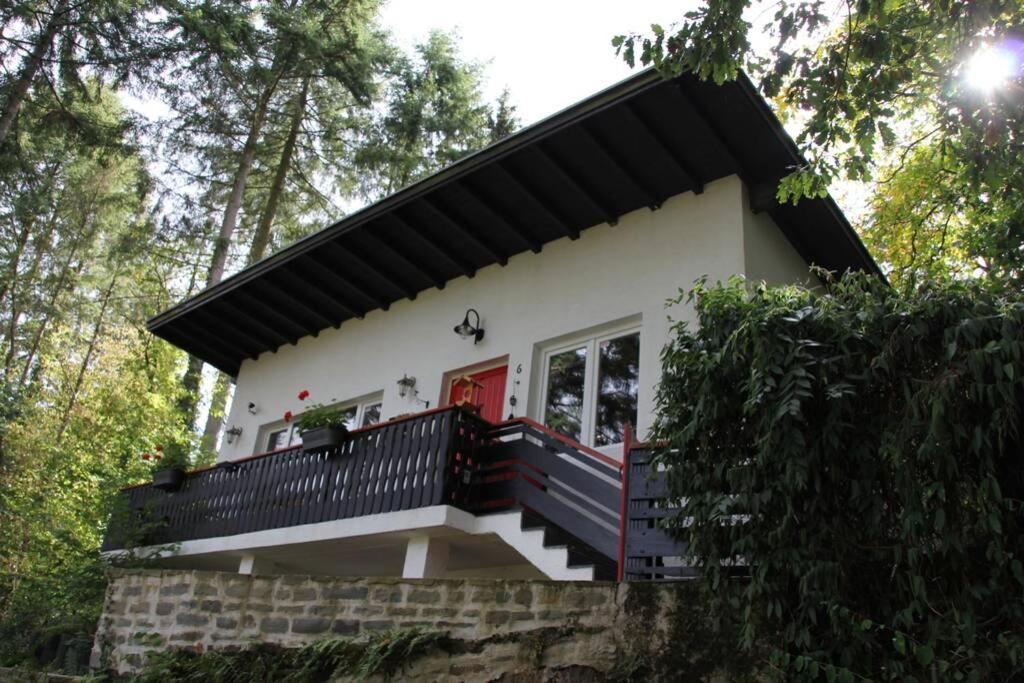 une petite maison blanche avec un toit noir dans l'établissement The Vianden Cottage - Charming Cottage in the Forest, à Vianden