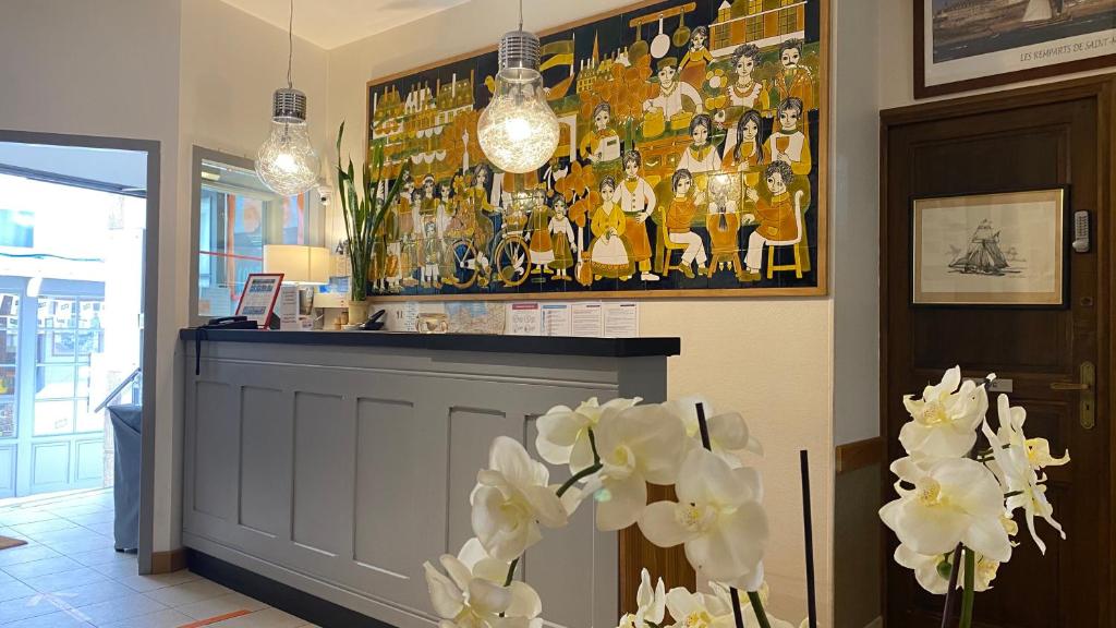 a bar with white flowers and a picture on the wall at Hôtel La Porte Saint Pierre-Logis Hôtel Intra Muros in Saint Malo