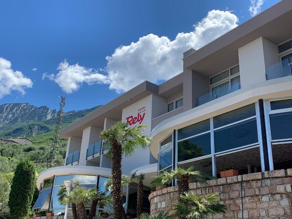 a building with palm trees in front of it at Hotel Residence Rely in Brenzone sul Garda