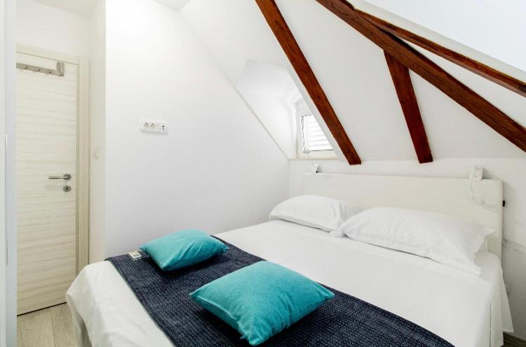 a white bed with blue pillows in a room at Apartman Roseta in Dubrovnik