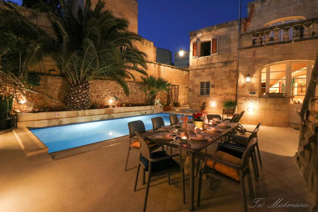 a dining table and chairs next to a swimming pool at Ta' Matmura Farmhouse in Għarb