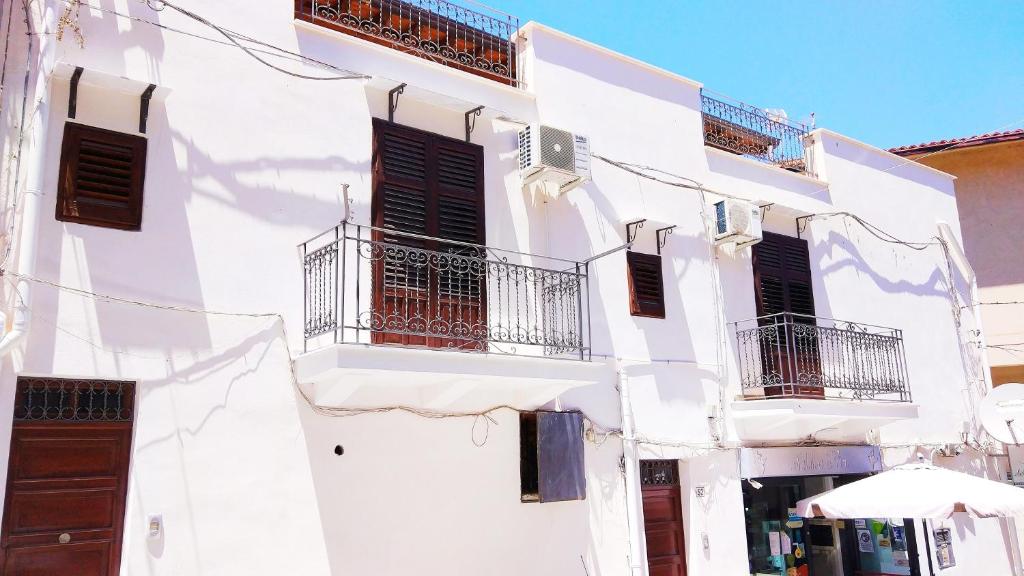 a white building with black shutters and balconies at Gurgiolo New Apartment in Trabia