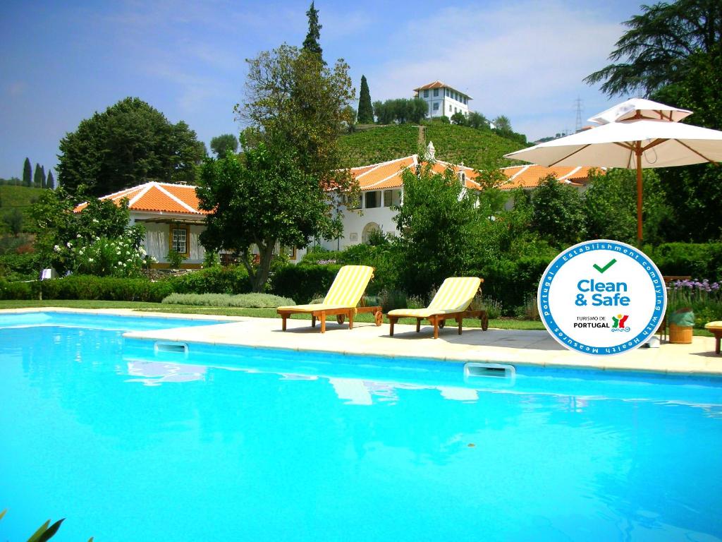 a swimming pool with two chairs and an umbrella at Casa da Azenha in Peso da Régua