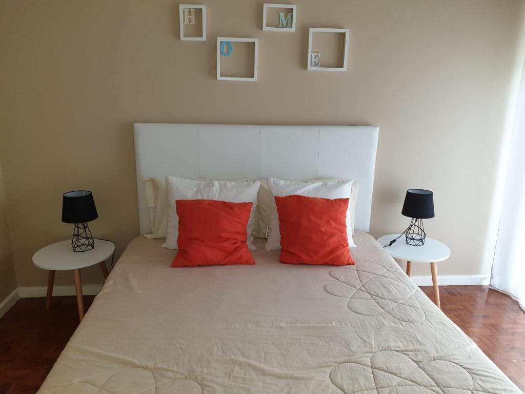 a bedroom with a bed with red pillows and two tables at Alegria Downtown Apartments in Porto