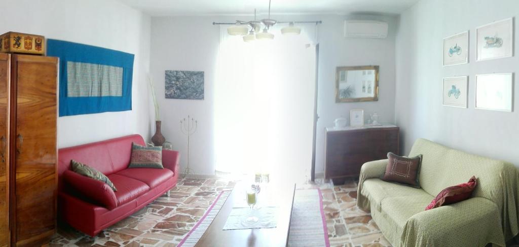 ein Wohnzimmer mit 2 Stühlen und einem roten Sofa in der Unterkunft Pà Blanc B&B in Alghero