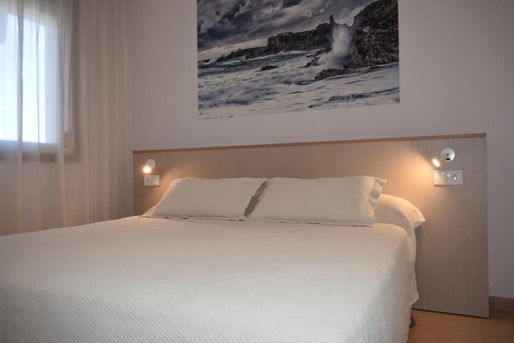 a bedroom with a white bed with a painting on the wall at Apartamentos VIDA Versus in Sanxenxo