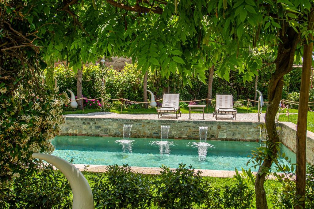 uma piscina com duas cadeiras e uma fonte em PALAZZO DEL CAPITANO Wellness & Relais - Luxury Borgo Capitano Collection em San Quirico dʼOrcia