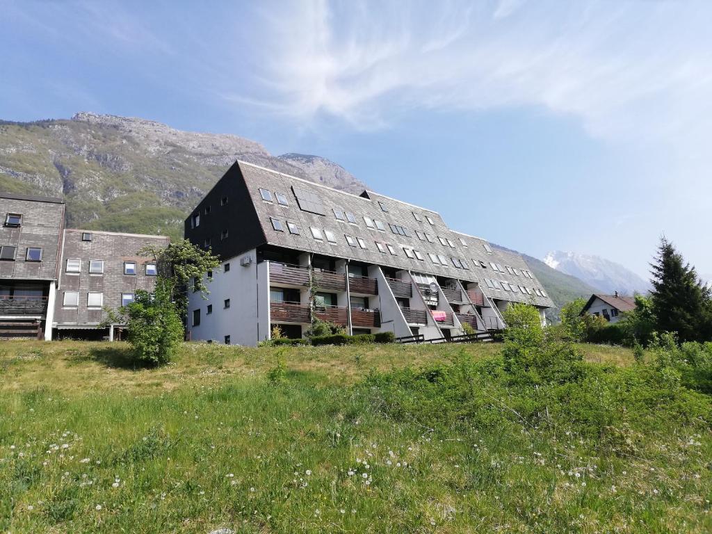 Ein Gebäude auf einem Feld mit Bergen im Hintergrund in der Unterkunft Alpine Relax Bovec in Bovec
